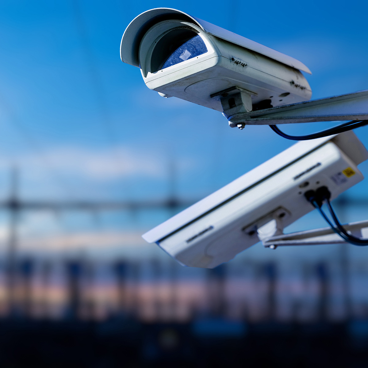 Security camera in foreground. Blurred background of powerlines in the distances.