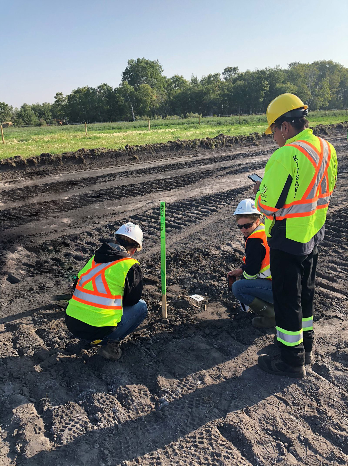 Inspection officers and an Indigenous Monitor mark an area on a pipeline right of way.