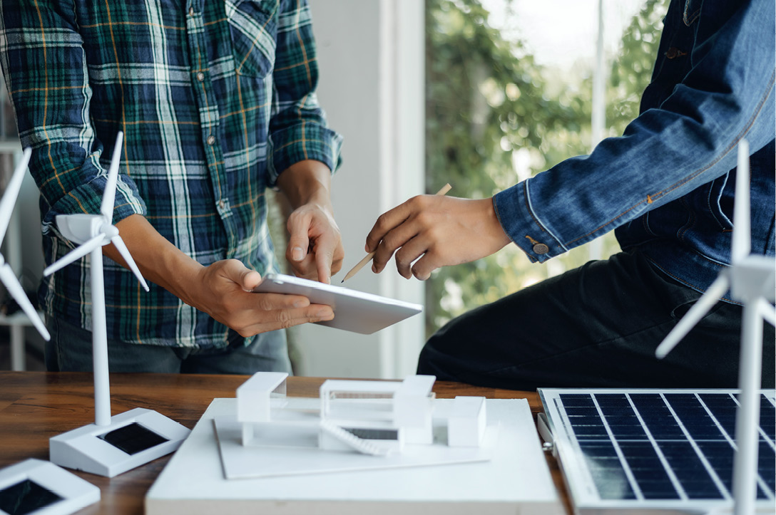 Les ingénieurs pointant la tablette avec leurs mains tout en discutant de la conception et de l’utilisation de l’énergie renouvelable éolienne et solaire.