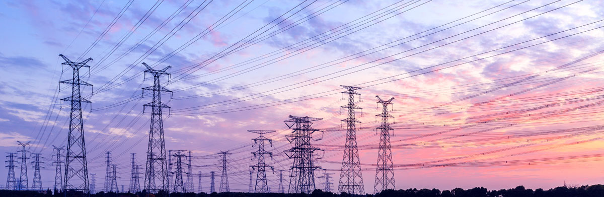 Une rangée de lignes de transport d’électricité au coucher du soleil.