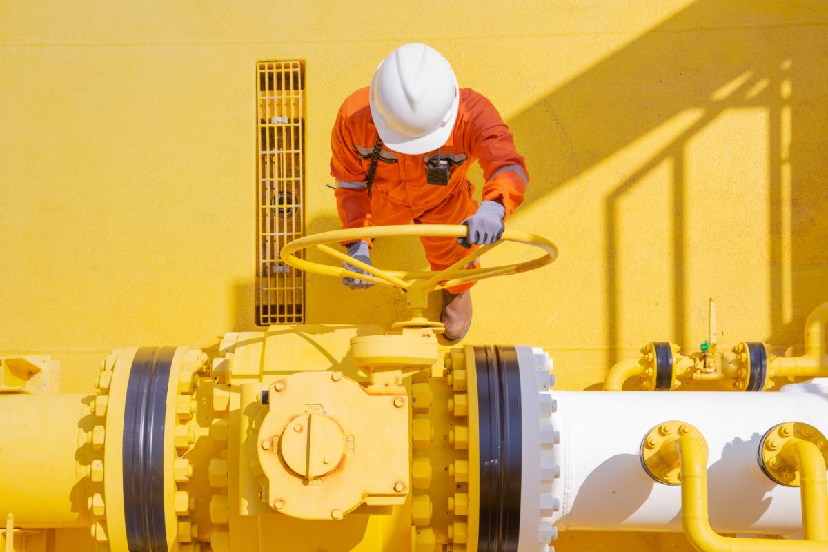 Travailleur opérant une vanne de pipeline.