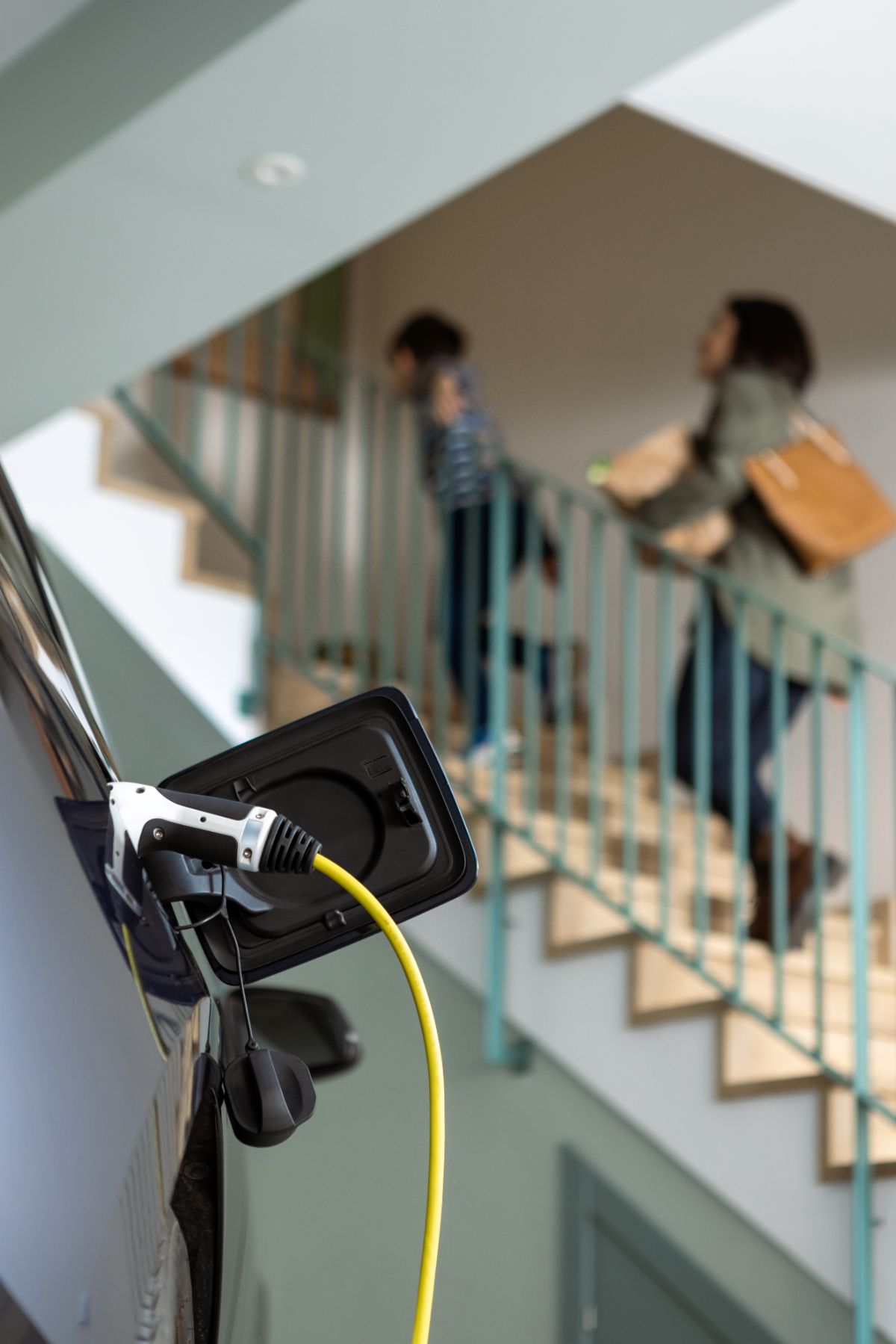 Mère et fils entrant à la maison pendant que la voiture électrique se charge dans le garage.