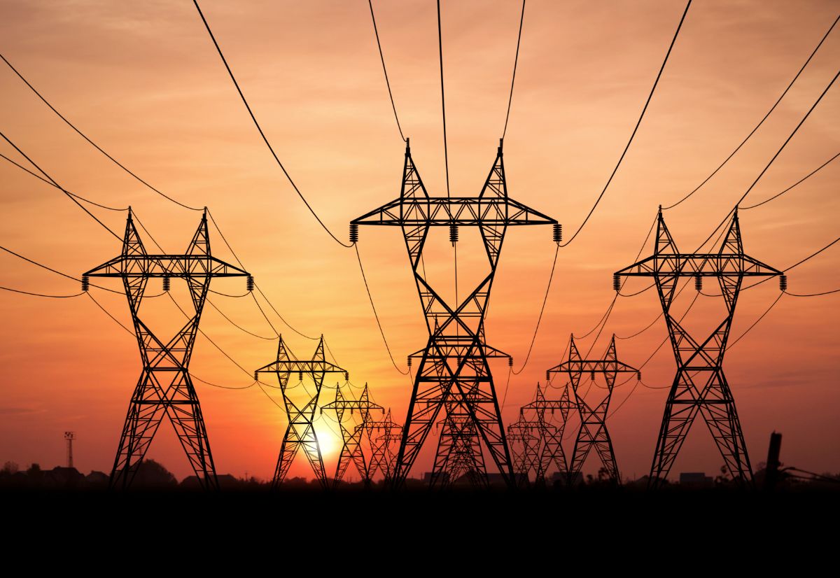 Pylônes et fils de transport d’électricité au coucher du soleil.