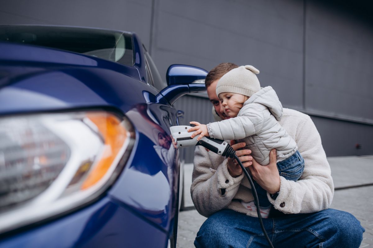 Père expliquant à sa fille comment recharger un véhicule électrique.