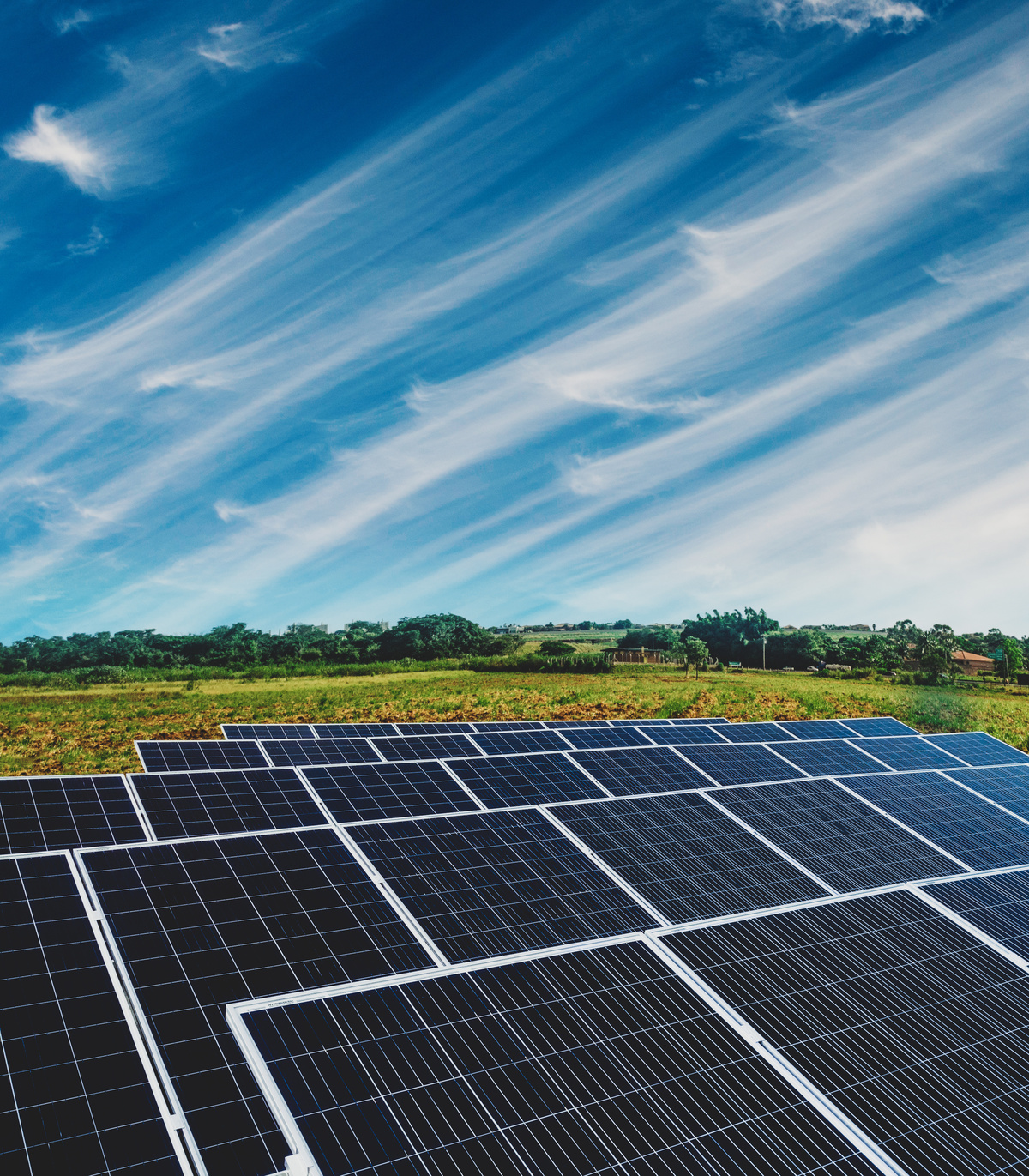 Solar panels in a field, overhead a beautiful blue sky with clouds.