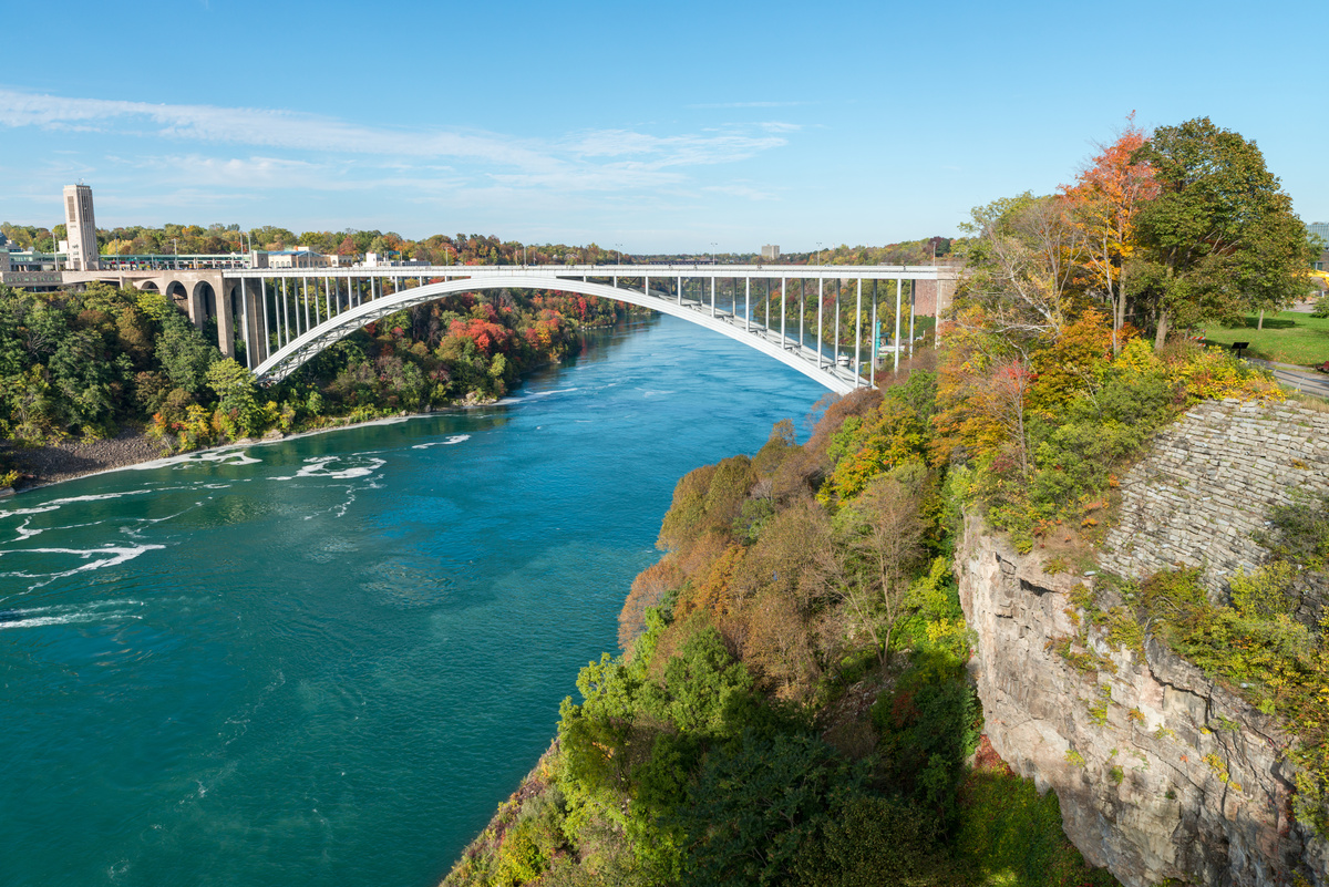 Rainbow bridge between U.S. and Canada and the surrounding Niagara riverbank on a sunny day.