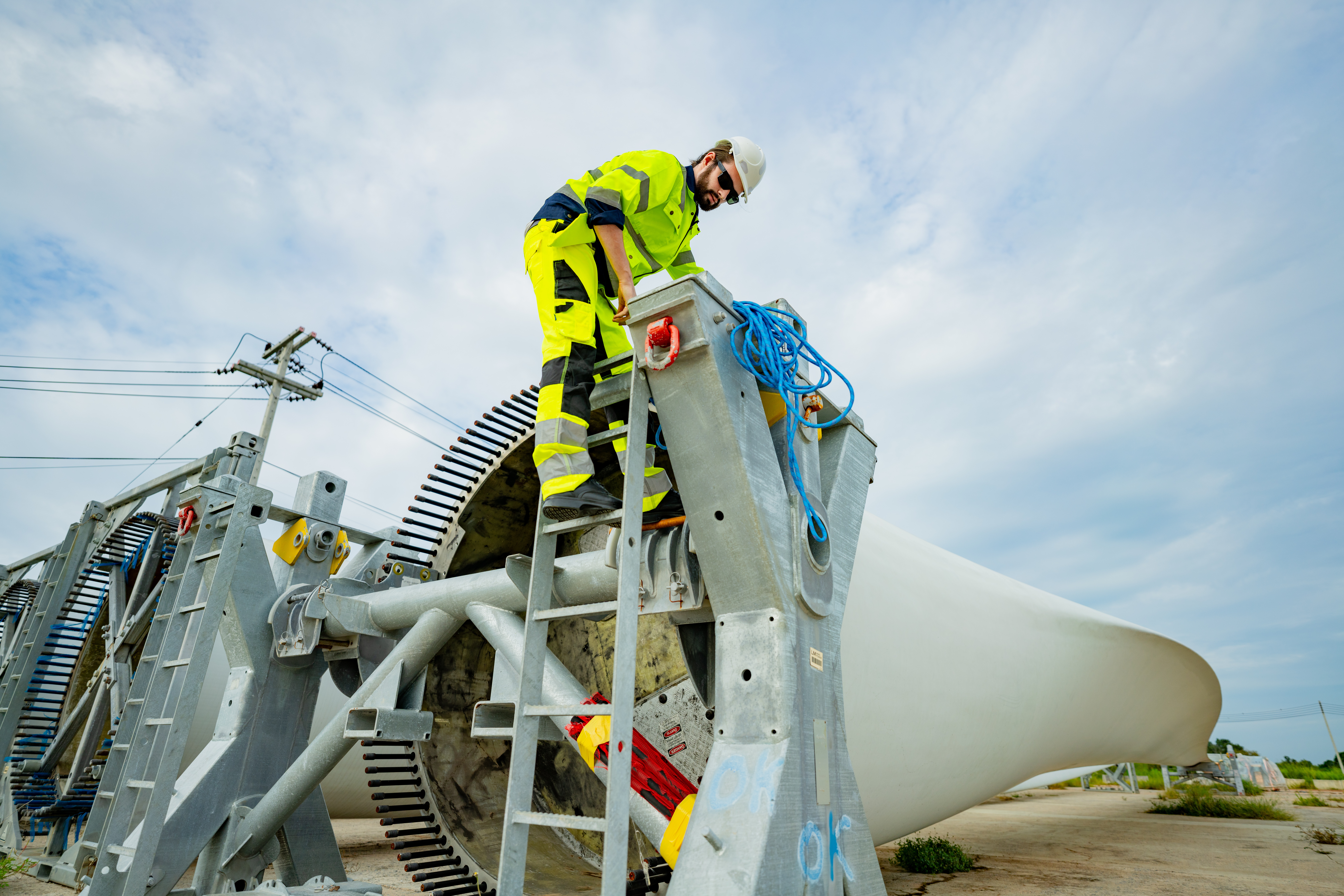 Worker climbs maintenance ladder to inspect large wind turbine generator in a renewable energy field.