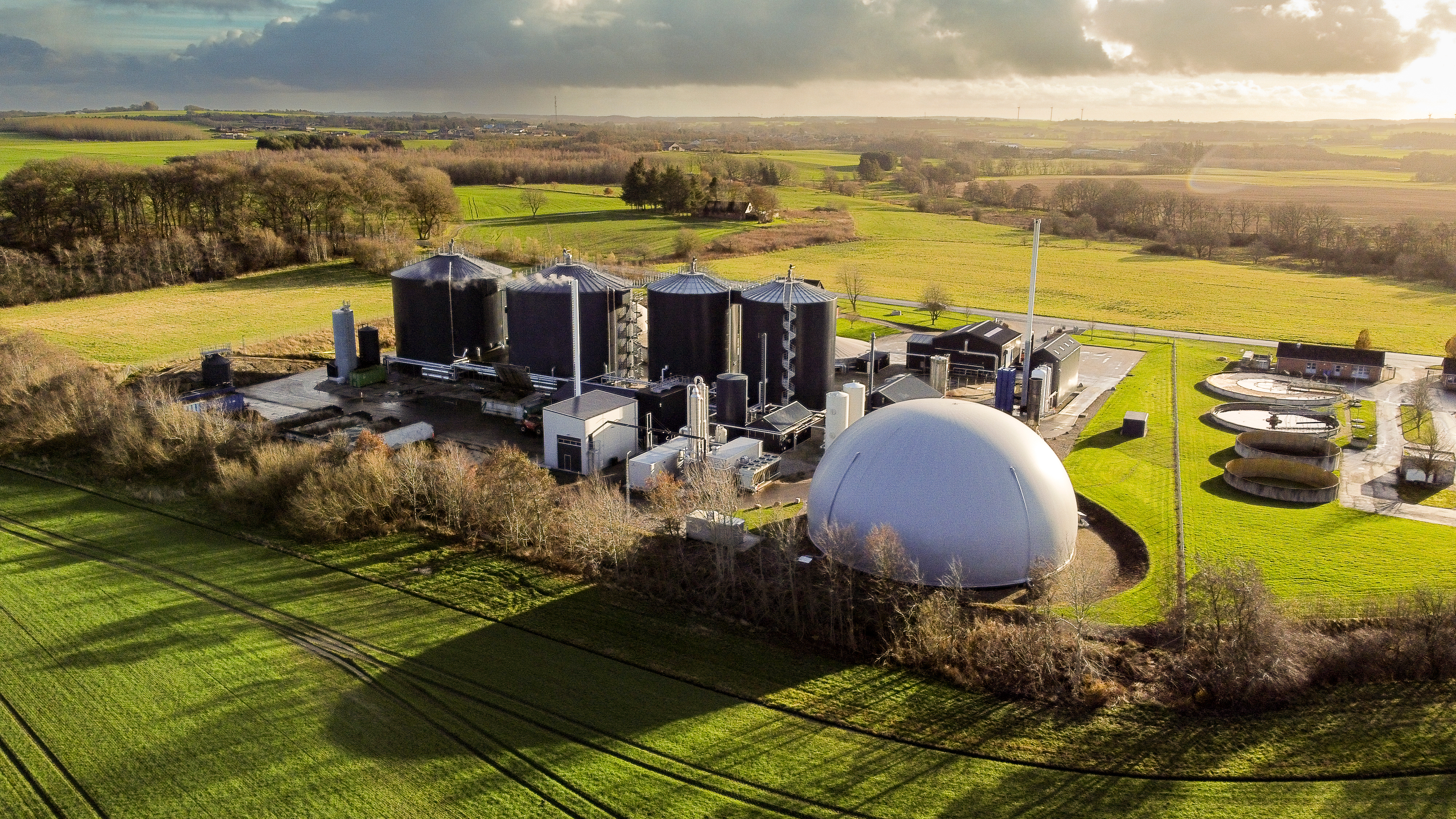 Aerial view of a large biogas production facility surrounded by green farmland in Denmark, highlighting renewable energy infrastructure and sustainable rural technology.