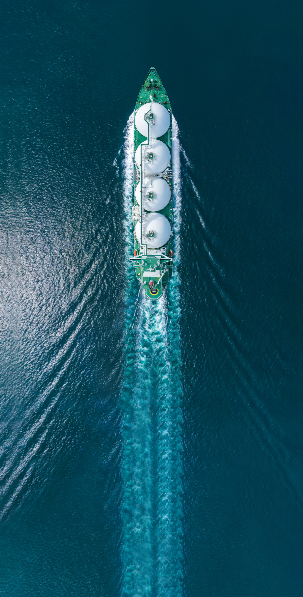 Aerial top view of LNG (Liquified Natural Gas) tanker ship with wake behind the ship in the ocean.
