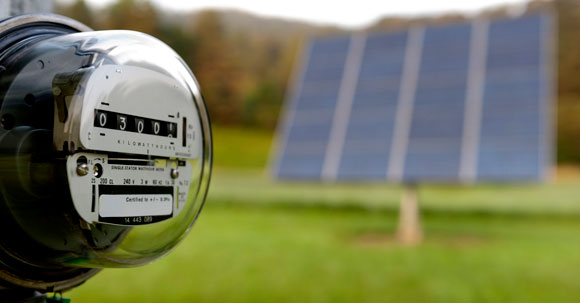 Un compteur de gaz en avant-plan et un panneau solaire hors champ, en arrière-plan