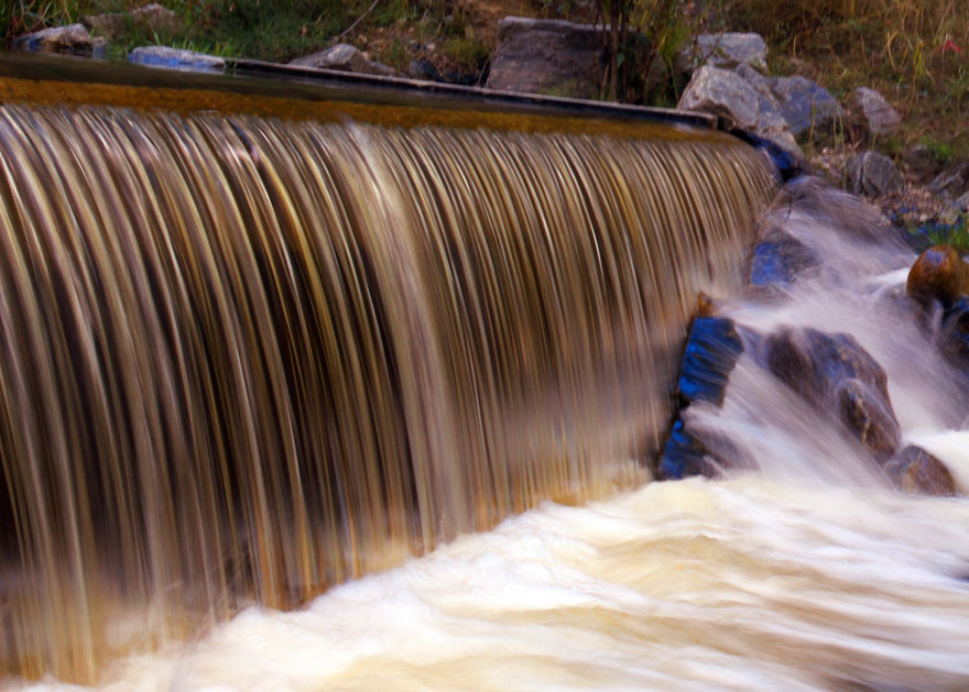 Image détaillée d’eau qui s’écoule d’un barrage et de roches de rivière