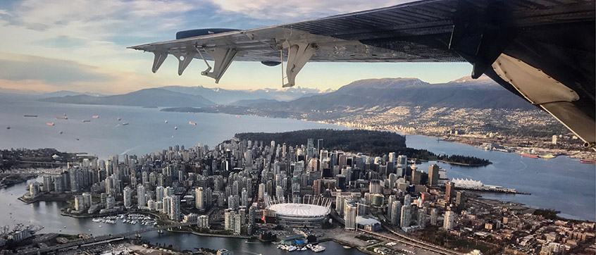 Vue aérienne de la partie ouest de Vancouver montrant des navires-citernes dans l’inlet Burrard et une chaîne de montagnes au loin.