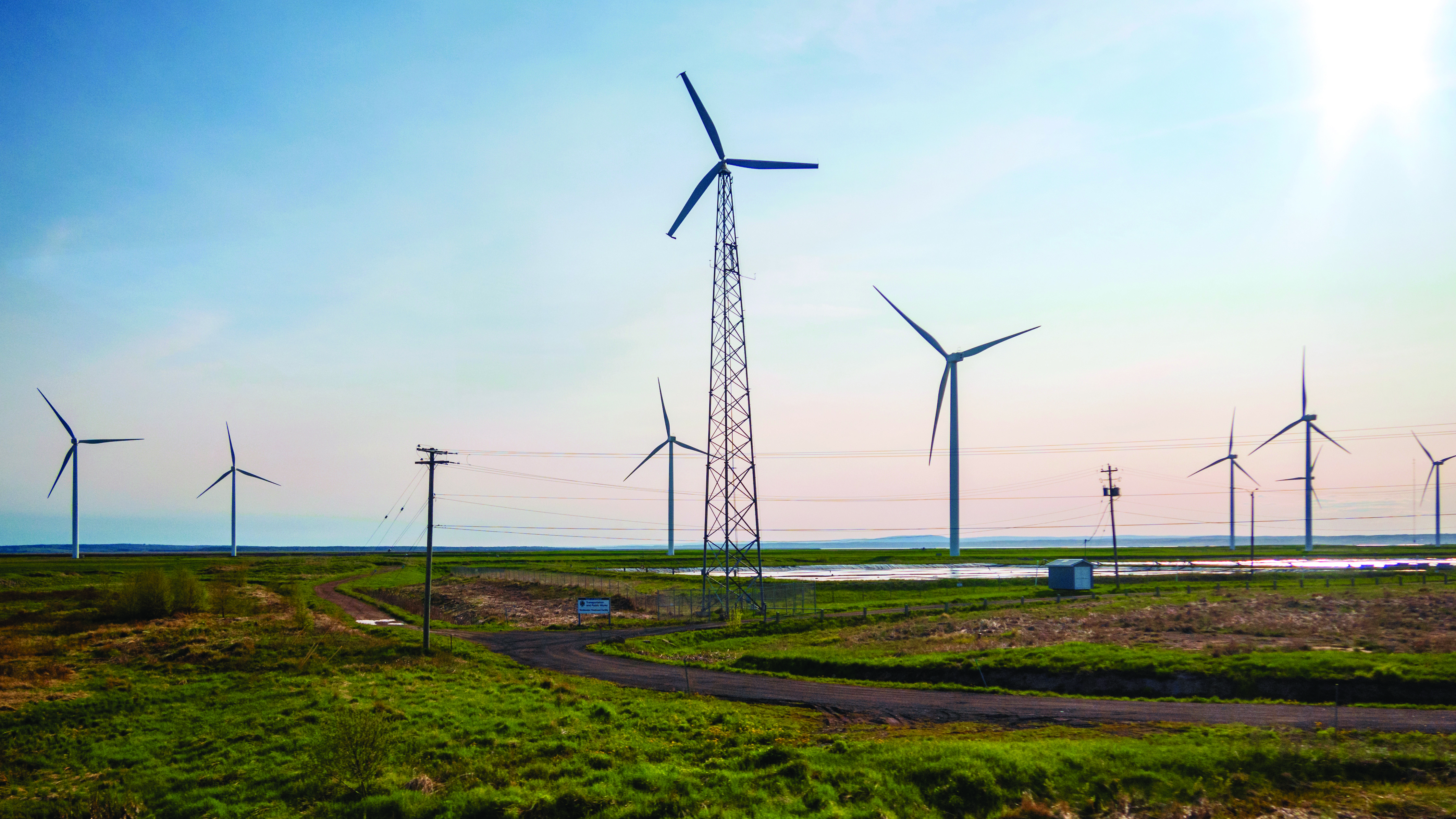 Éoliennes près d’une route de gravier, dans un parc près d’Amherst, en Nouvelle-Écosse, tôt le matin, sous un ciel partiellement couvert.