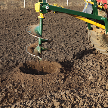 Terrière forant un trou dans un champ pour planter un arbre ou installer un poteau de clôture.
