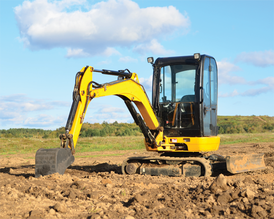 Mini excavatrice creusant le sol dans un champ.