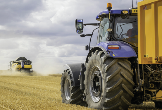 Tracteur agricole tirant une grosse remorque dans un champ.