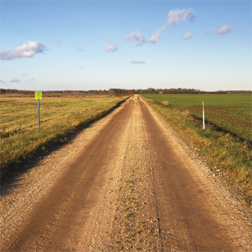 Chemin de terre longé de marqueurs de pipelines de chaque côté