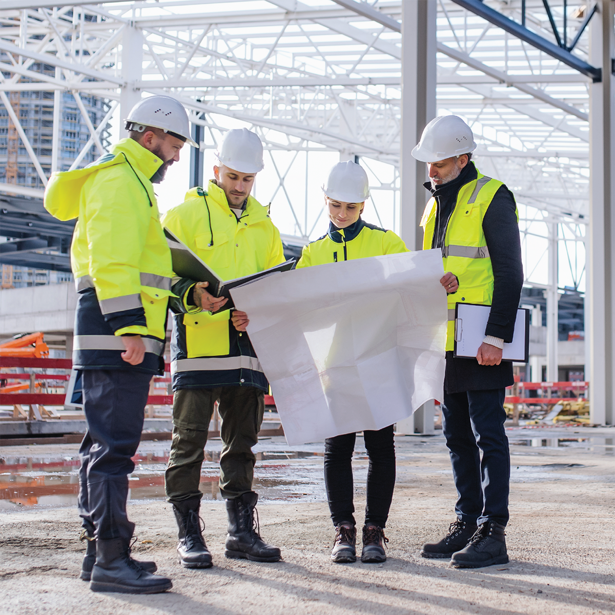 Groupe d’ingénieurs examinant des plans sur un chantier de construction