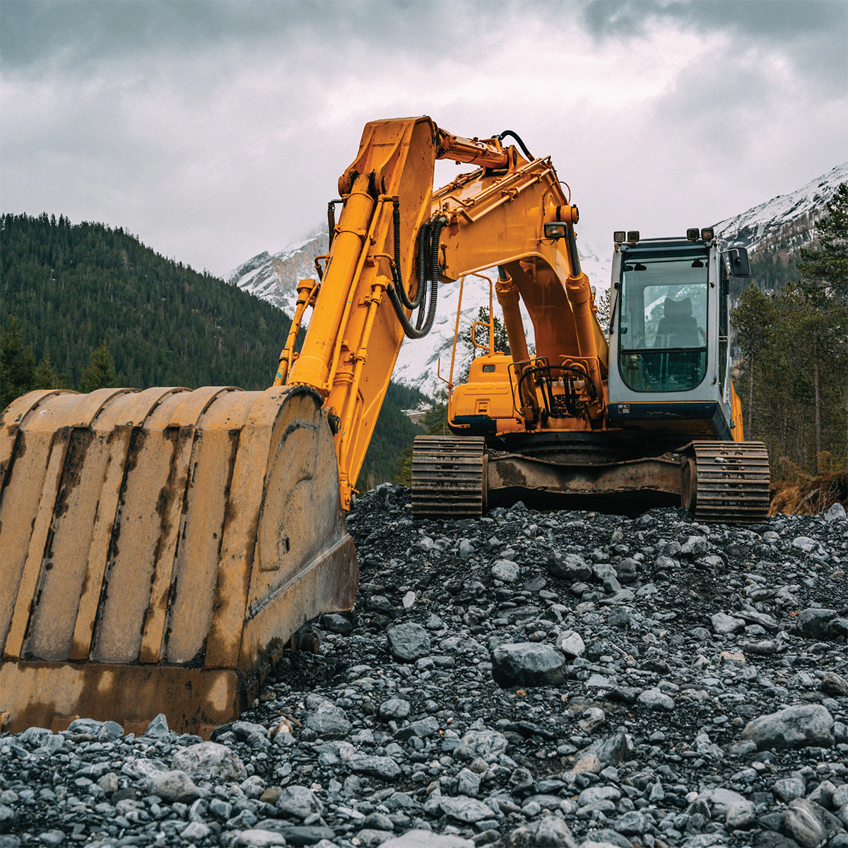 Excavateur à chenilles en action sur des pierres et du gravier