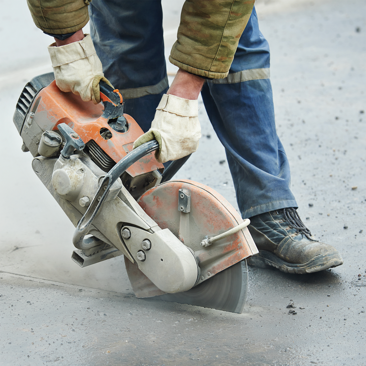Travailleur de la construction effectuant des travaux d’entretien sur une route à l’aide d’une scie