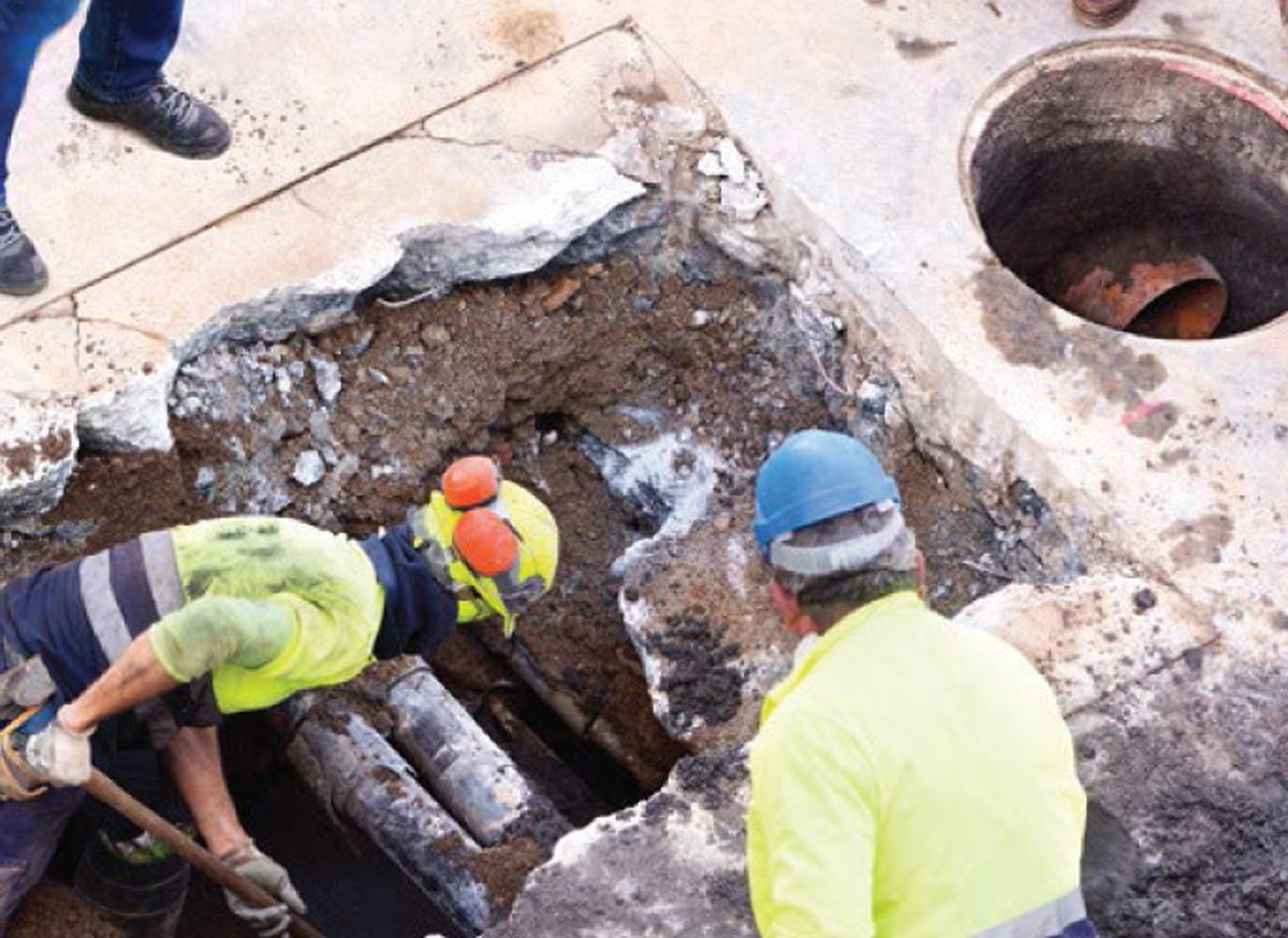 Construction workers digging around a buried pipe